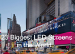 Times Square street scene with oversized LED billboards and pedestrians; the article title '23 Biggest LED Screens in the World' is overlaid on the image.
