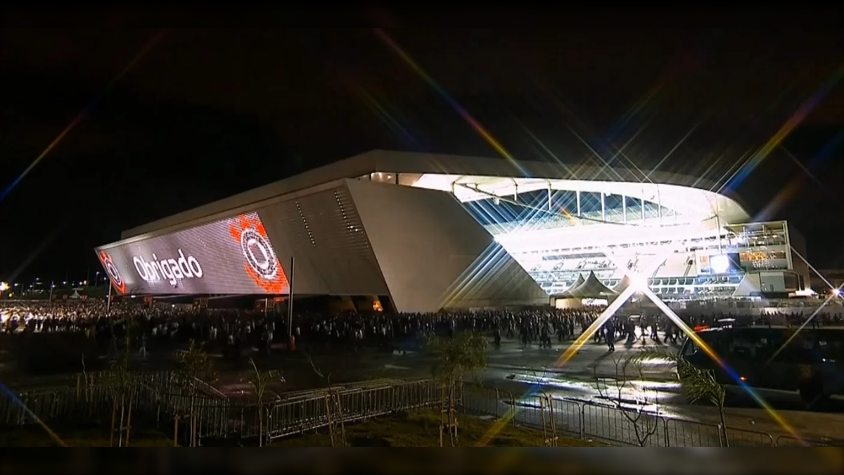 Arena Corinthians Facade Biggest LED Screen Project LED Display Manufacturer in China EagerLED Night view of a futuristic stadium with bright exterior lighting a crowd gathered outside and the word Obrigado projected on the side
