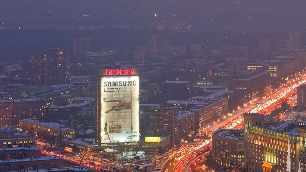 Hydroproject Institute Biggest LED Screen Project LED Display Manufacturer in China EagerLED Nighttime cityscape with a large Samsung advertisement on a tall building snowy rooftops and a curving line of red taillights along a busy street