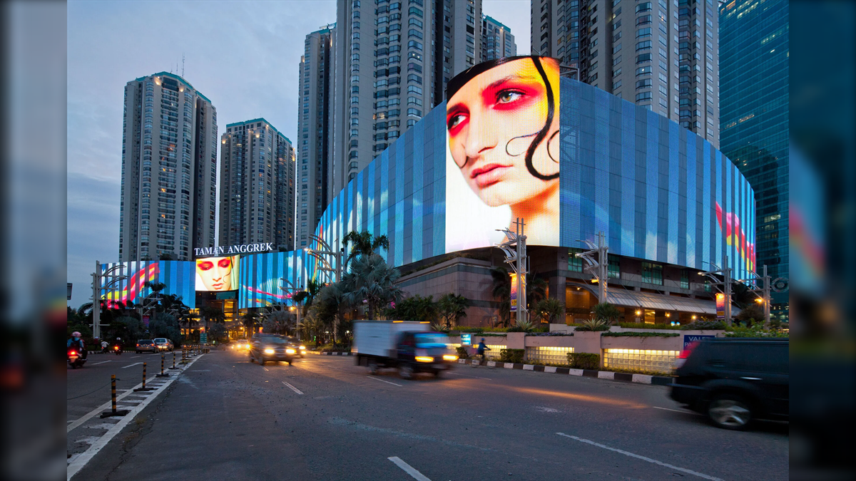 Mall Taman Anggrek Biggest LED Screen Project LED Display Manufacturer in China EagerLED Facade of Taman Anggrek Mall with a giant LED screen showing a womans face against tall surrounding buildings and a busy street in the foreground at dusk