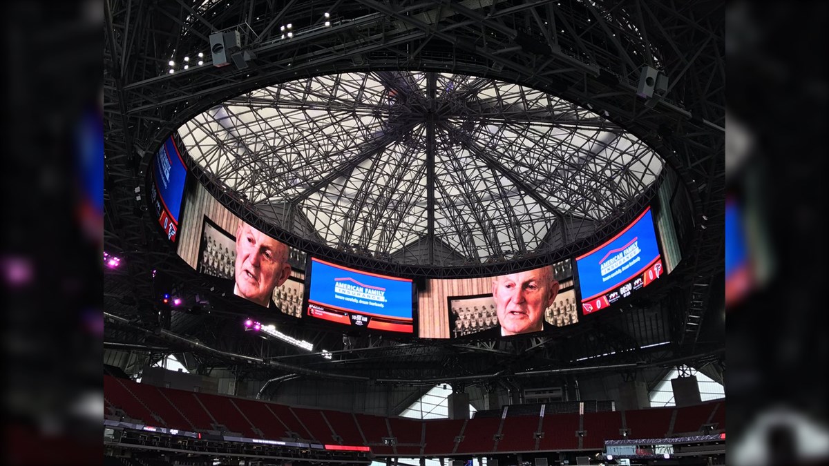 MercedesBenz Stadium Halo Biggest LED Screen Project LED Display Manufacturer in China EagerLED Circular video scoreboard suspended above a stadium floor showing a close up of an older mans face and blue event graphics around the ring of screens