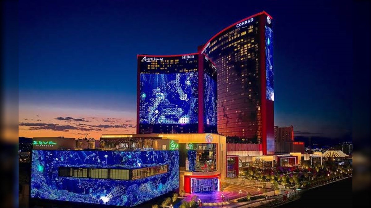 Resorts World West Tower Biggest LED Screen Project LED Display Manufacturer in China EagerLED Night view of a large illuminated hotel and casino complex with blue digital displays on the façade and a warm entrance area nearby