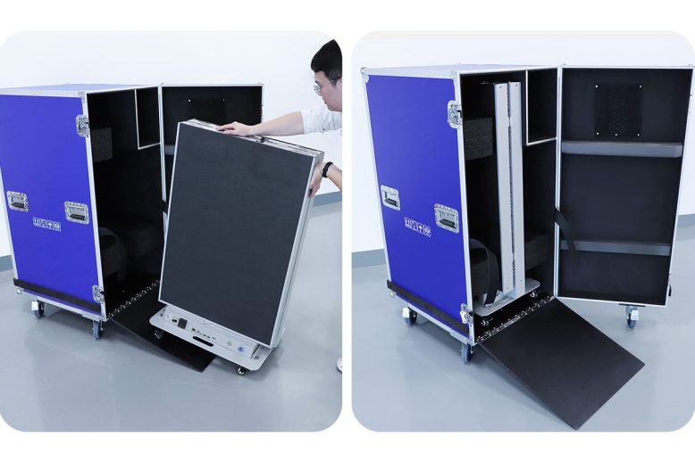 EA1920iP5 Panneau d'affichage LED intérieur 7 Person loading a large black equipment panel into an open blue wheeled flight case; gear is being prepared for transport in a studio setting, with the case on the floor and rack panel partly inserted into the case.