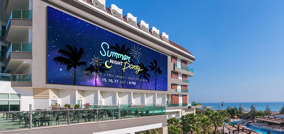 ホテルのファサードに設置されたLED広告スクリーンには、夏の夜のパーティーの広告が映し出されている。