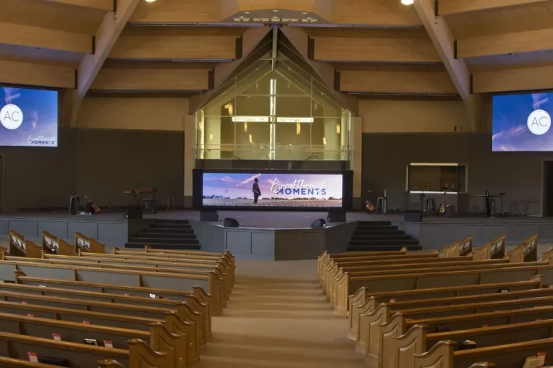 Church sanctuary with pew seating, two side displays and a central stage screen