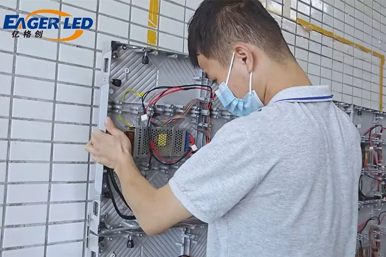 Technician mounting EA640F2 front-service LED cabinets on a wall frame