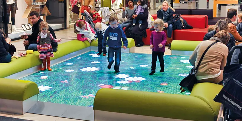 Children jumping on an interactive LED floor that shows flowers under each step
