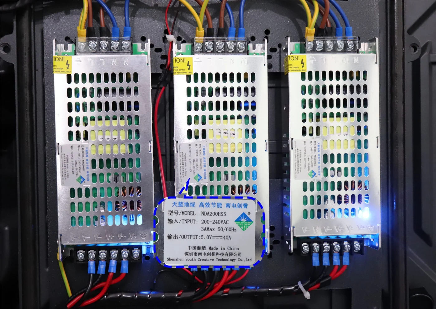 Tres fuentes de alimentación conectadas una al lado de la otra dentro de un gabinete de pantalla LED.