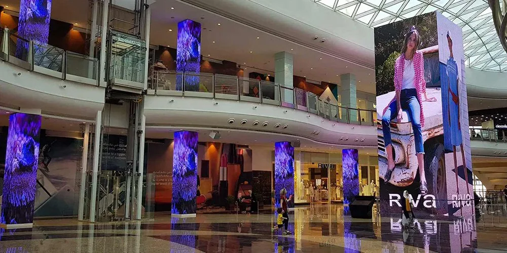Flexible LED screens wrapped around columns in a shopping mall atrium