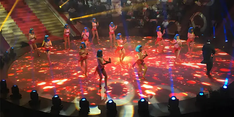 Performers dancing on a large LED floor display stage at an event