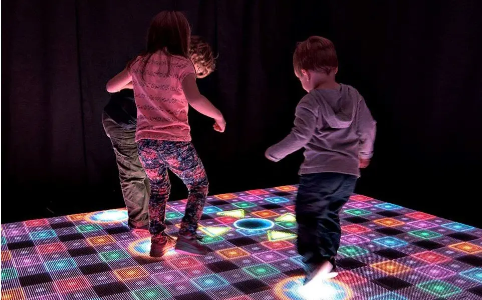 Two people dancing on an LED video dance floor at night