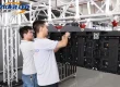 Two technicians installing rental LED cabinets on a hanging beam during an LED video wall installation